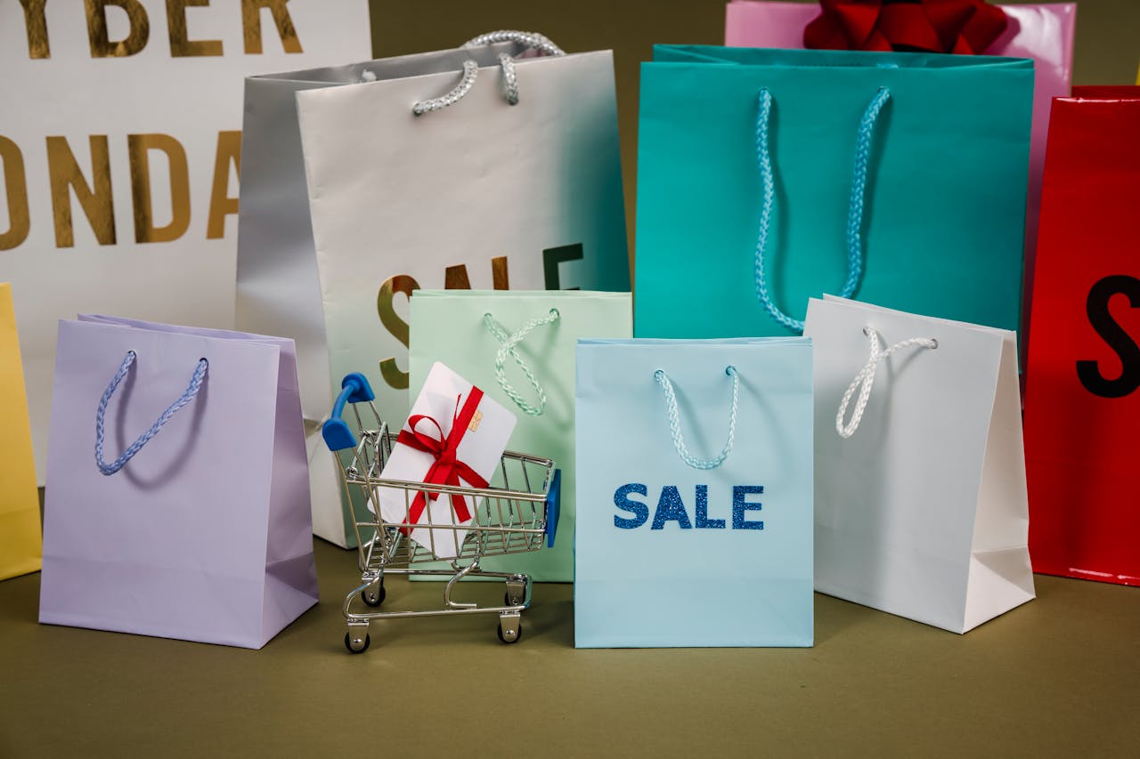 A mix of colorful shopping bags and a small cart displaying a discount gift.