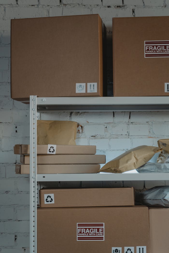 Stacked cardboard boxes with fragile labels on industrial shelves in a warehouse.